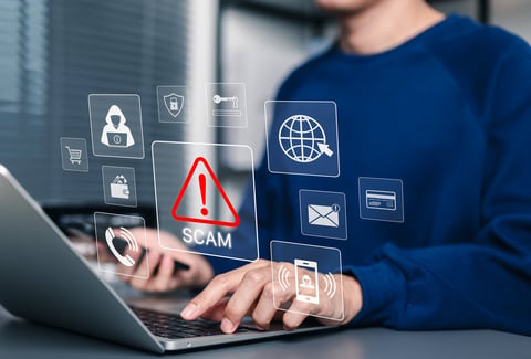 Scam Alert Warning with Cybersecurity Icons. Man holding smartphone while using laptop, warning sign for scams with icons online threats, phishing, cybersecurity, Unknown person, suspicious scammer,