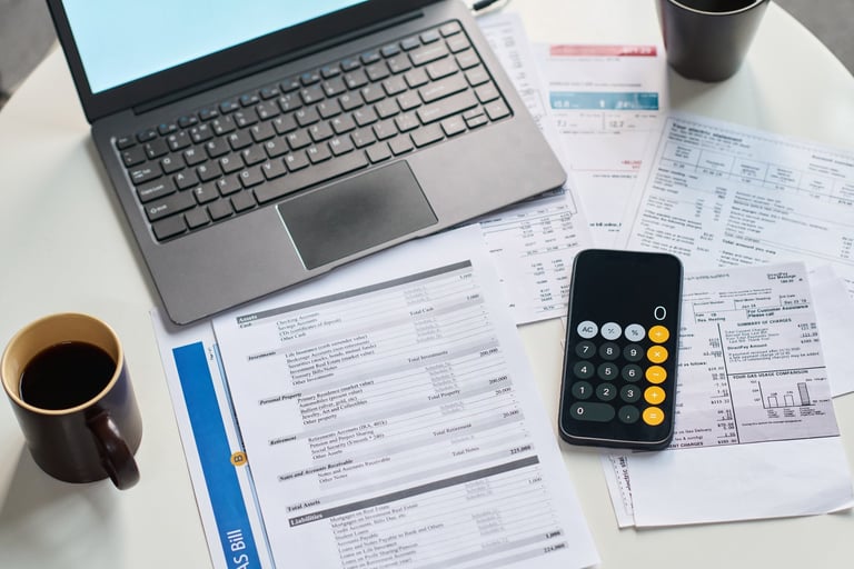 Closeup of financial documents, calculator, laptop and coffee cup on table showing tax forms