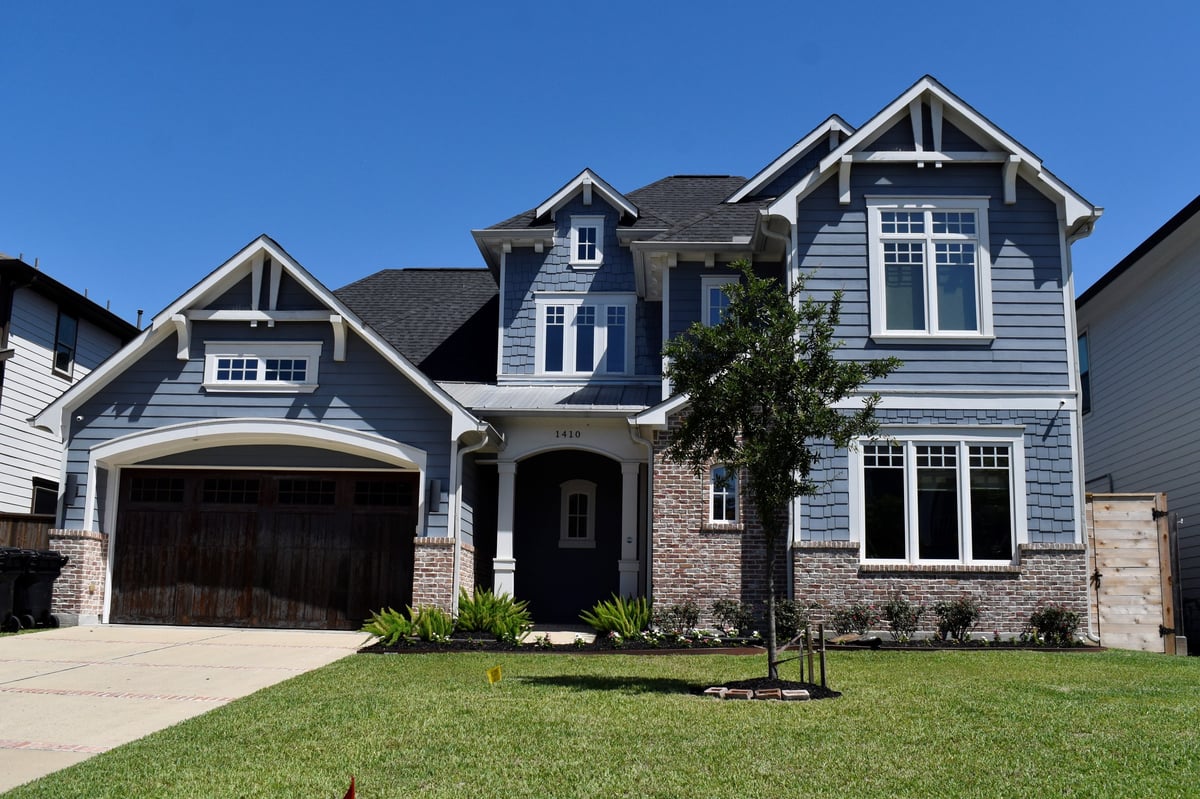 Luxurious suburban home with light blue facade and wooden garage door