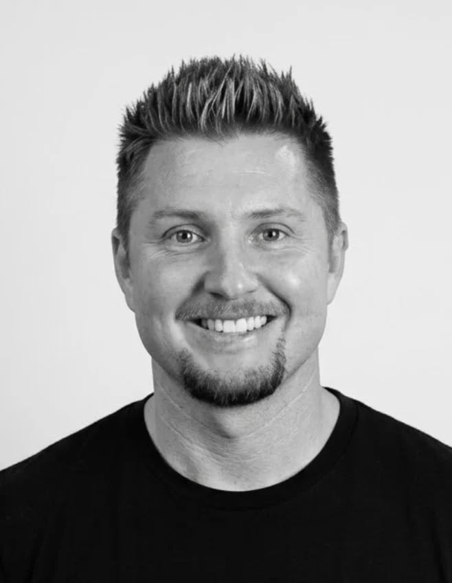 Smiling man with spiky black hair and goatee wearing a black t-shirt in a headshot photo