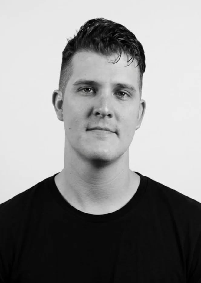 Black and white portrait of a man with dark hair wearing a black shirt against a light background